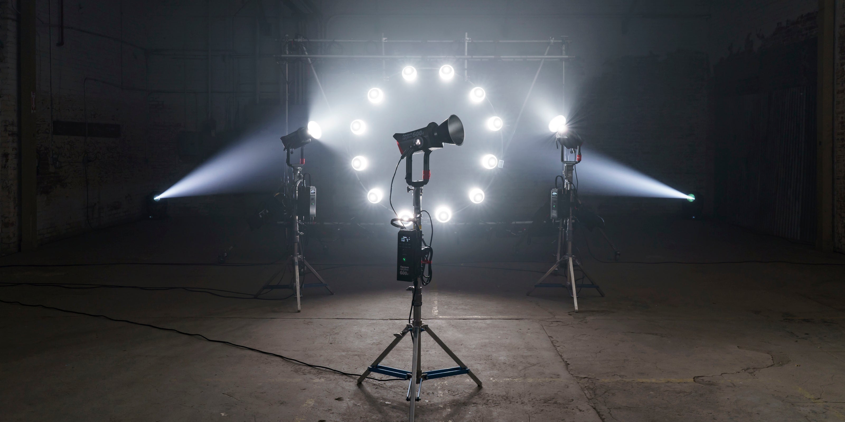 Aputure 600D on a lighting stand with other Aputure lighting fixtures in the background within an old warehouse.