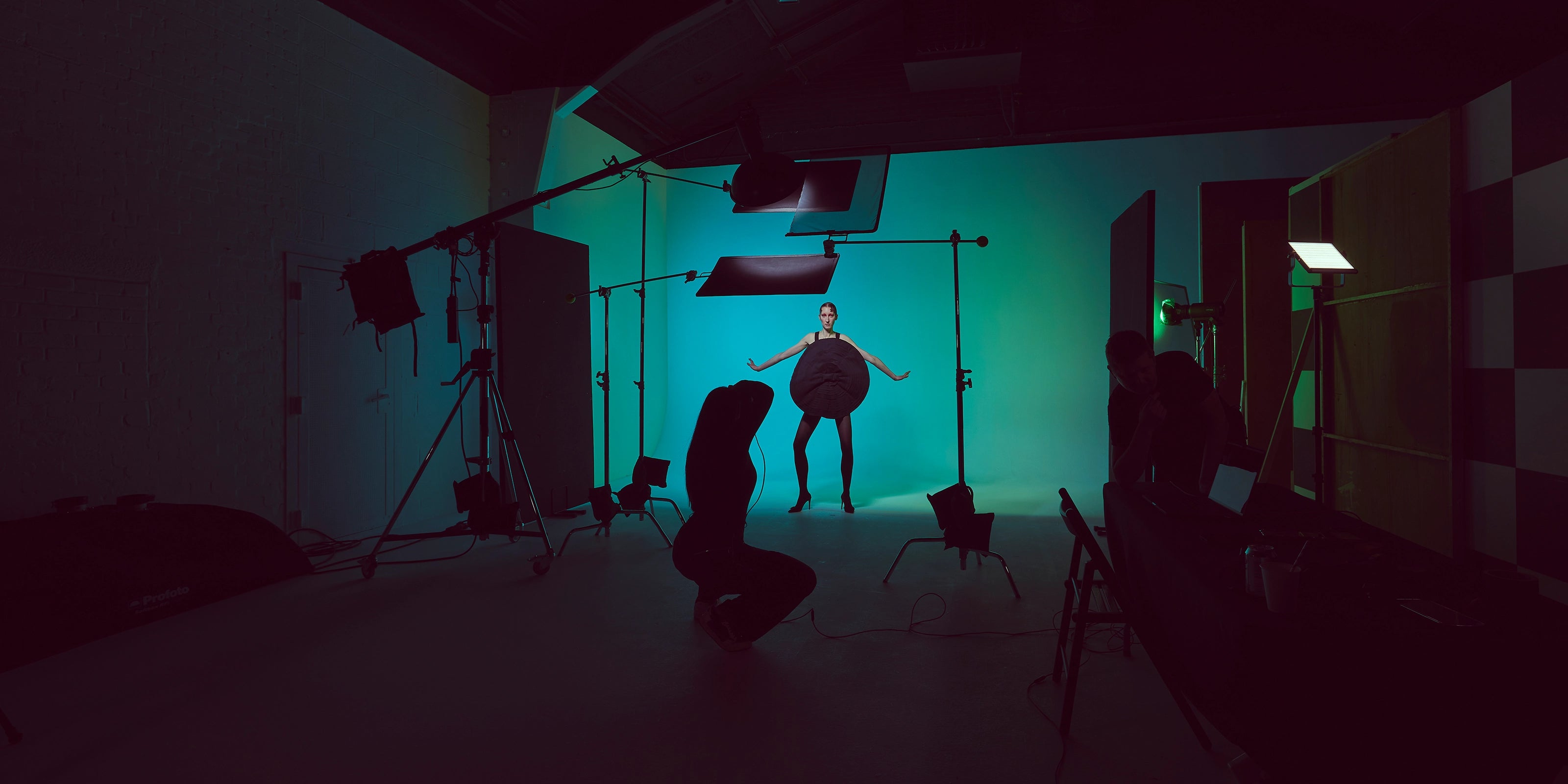Female model in a busy studio envioment with Profoto Pro-D3 flash lights on a teal coloured background.