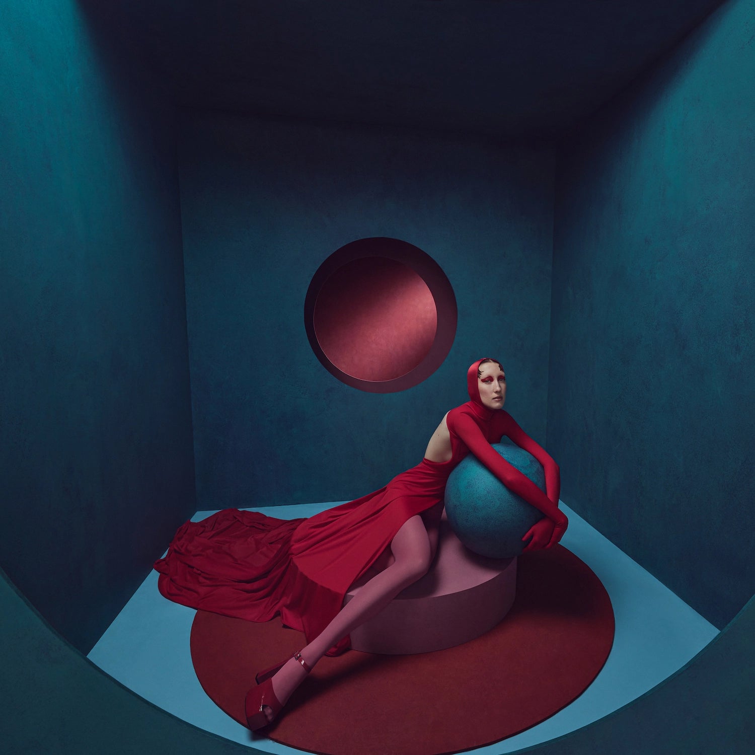 Model dressed in a red gown holds a round dark teal coloured ball. Image shot using the Profoto Pro-D3.