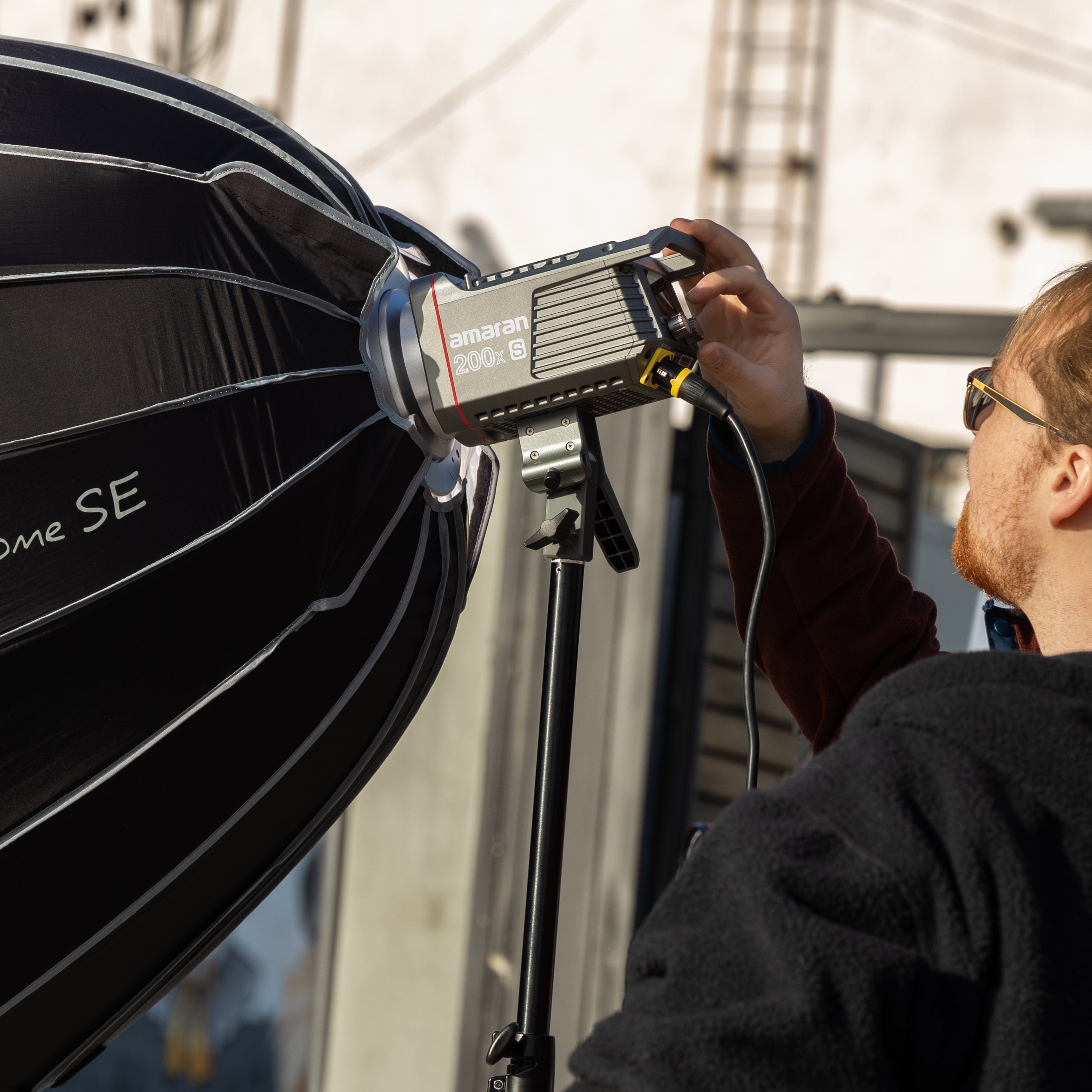 Photographer monitoring Amaran 200x S CoB light with Aputure Light Dome SE atttached.