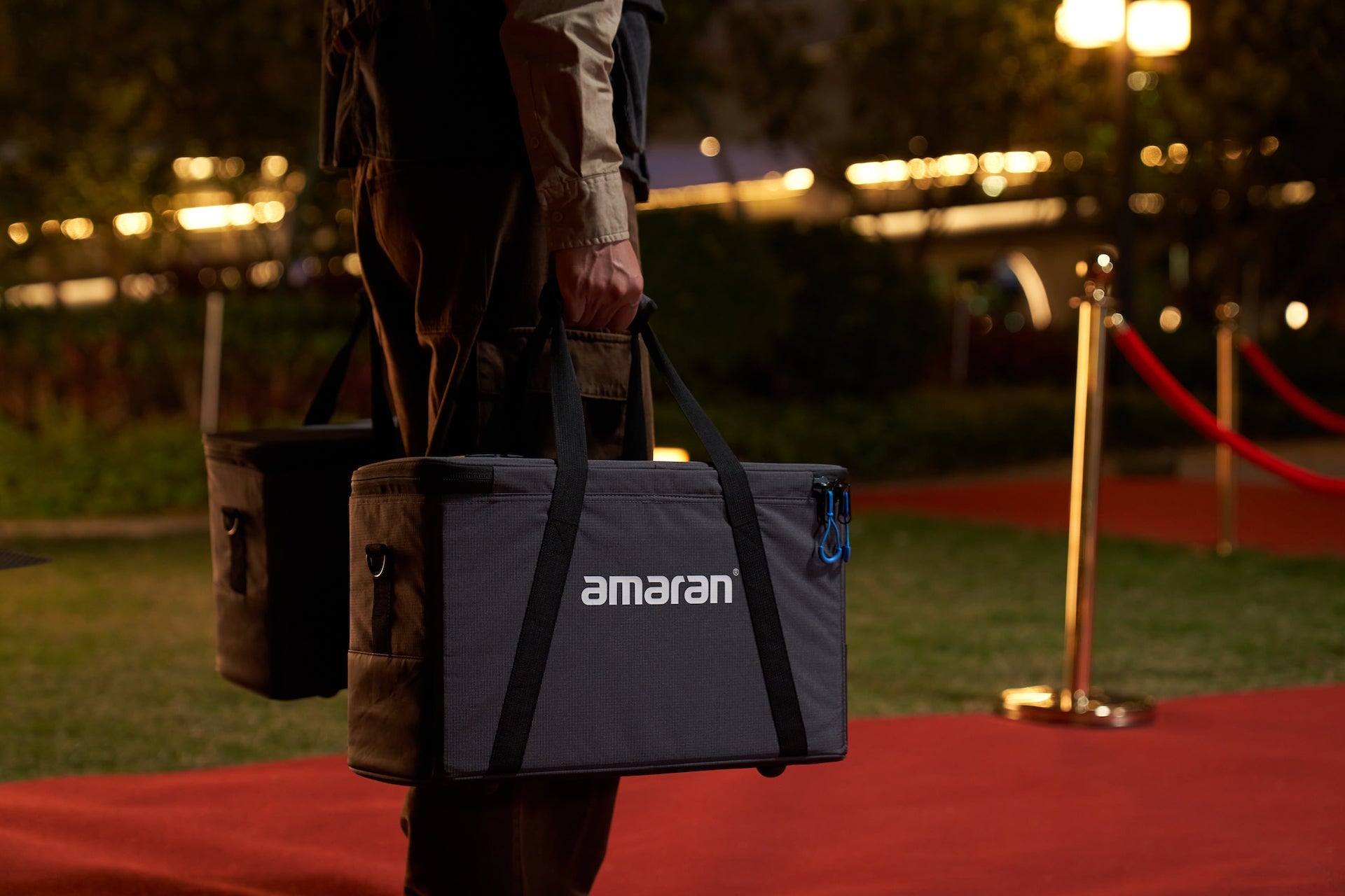Person holding two amaran Pano 60c Kits on a red carpet.