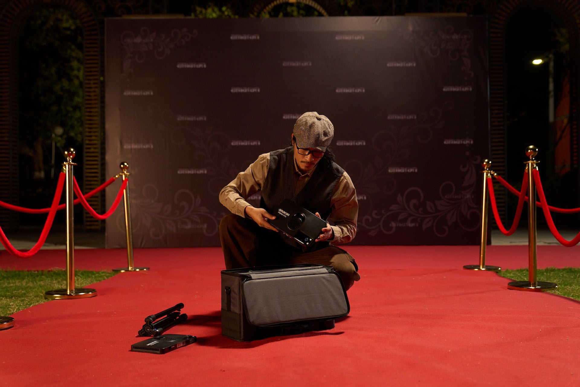Charcoal amaran Pano 60c Light Panel pictured with its case and accessories on a red carpet.