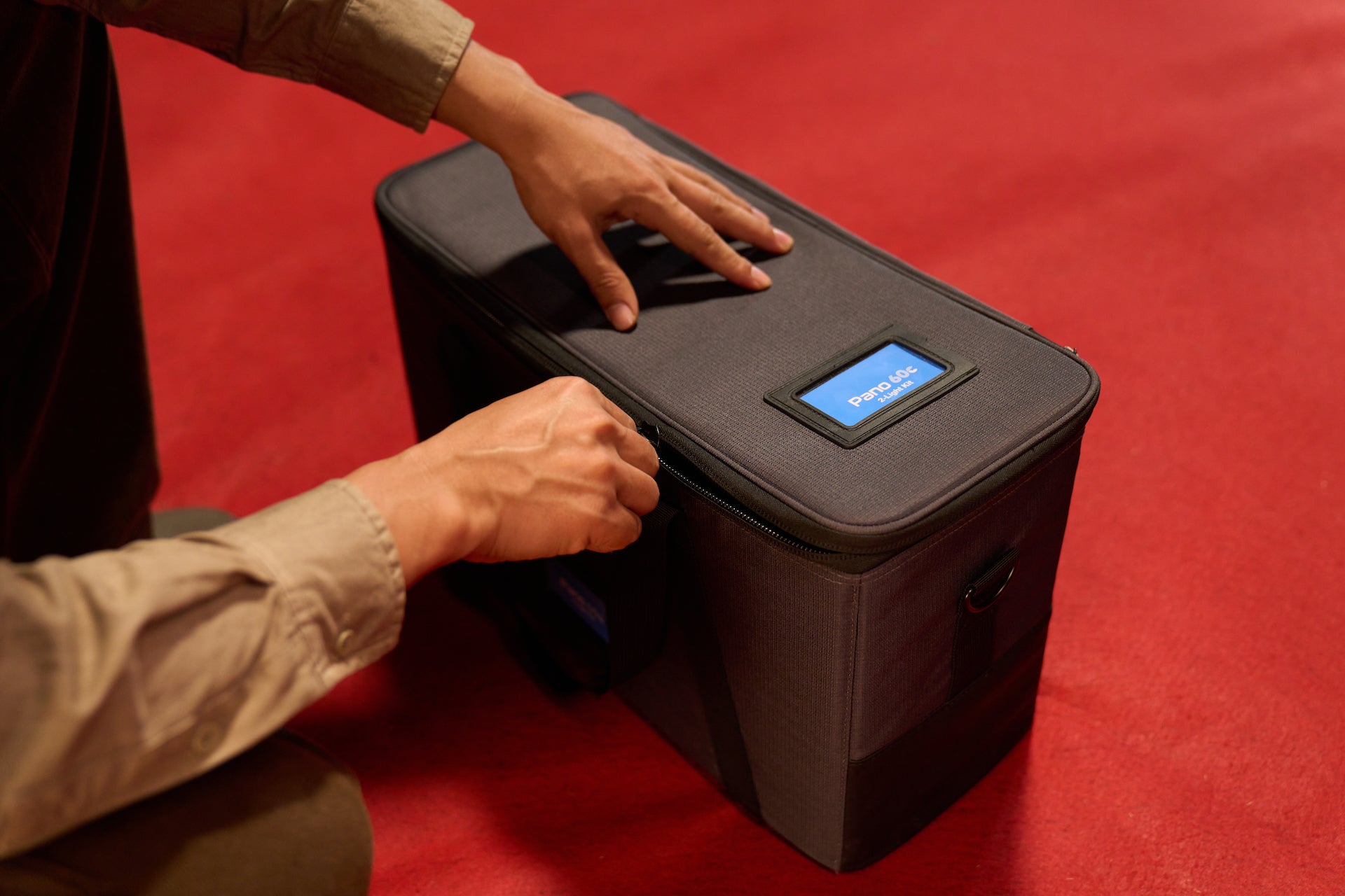 Person zipping up the case for an amaran Pano 60c 2 Light kit.