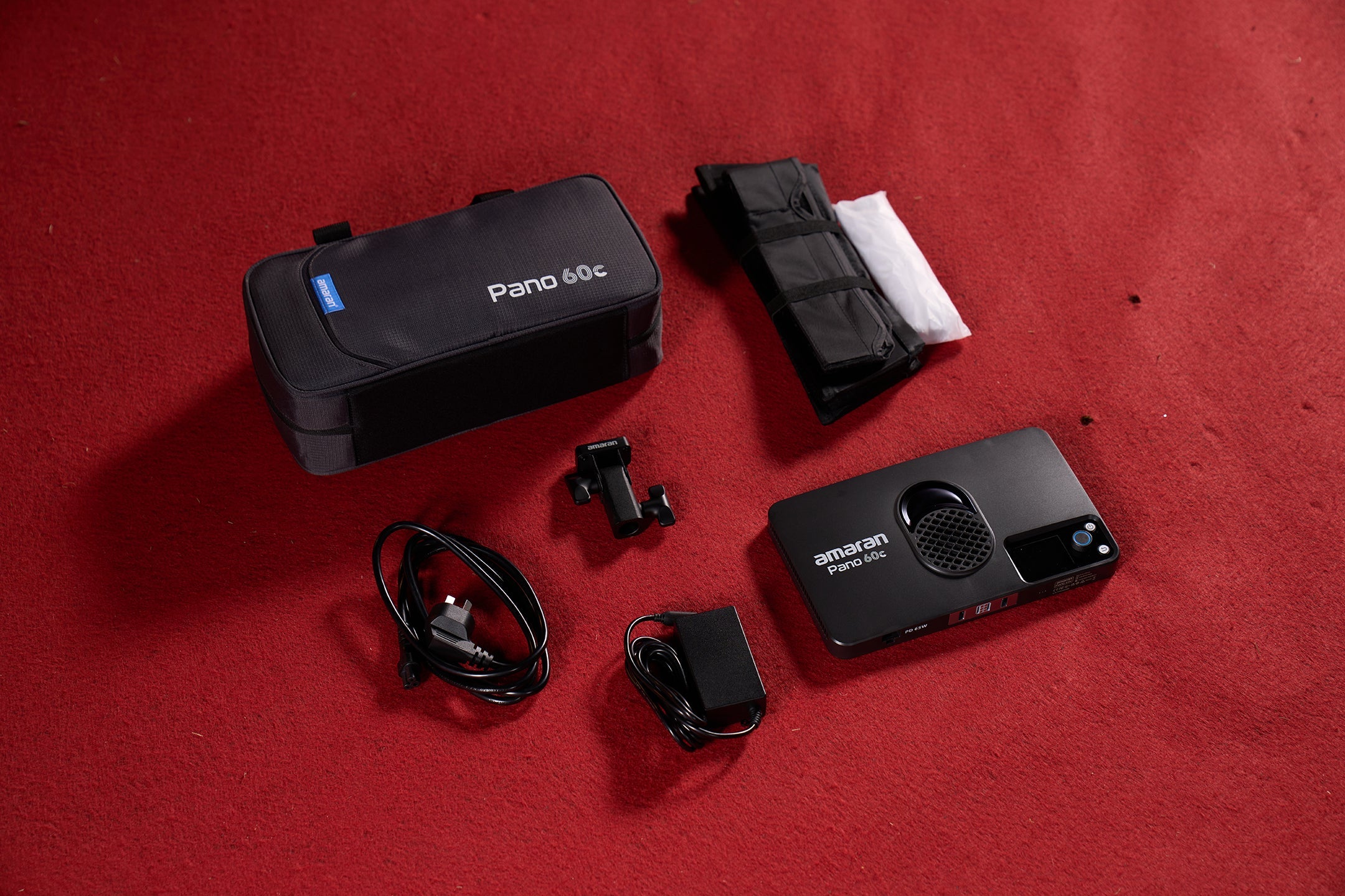 All components for the amaran Pano 60c Kit laid out on a red carpet.