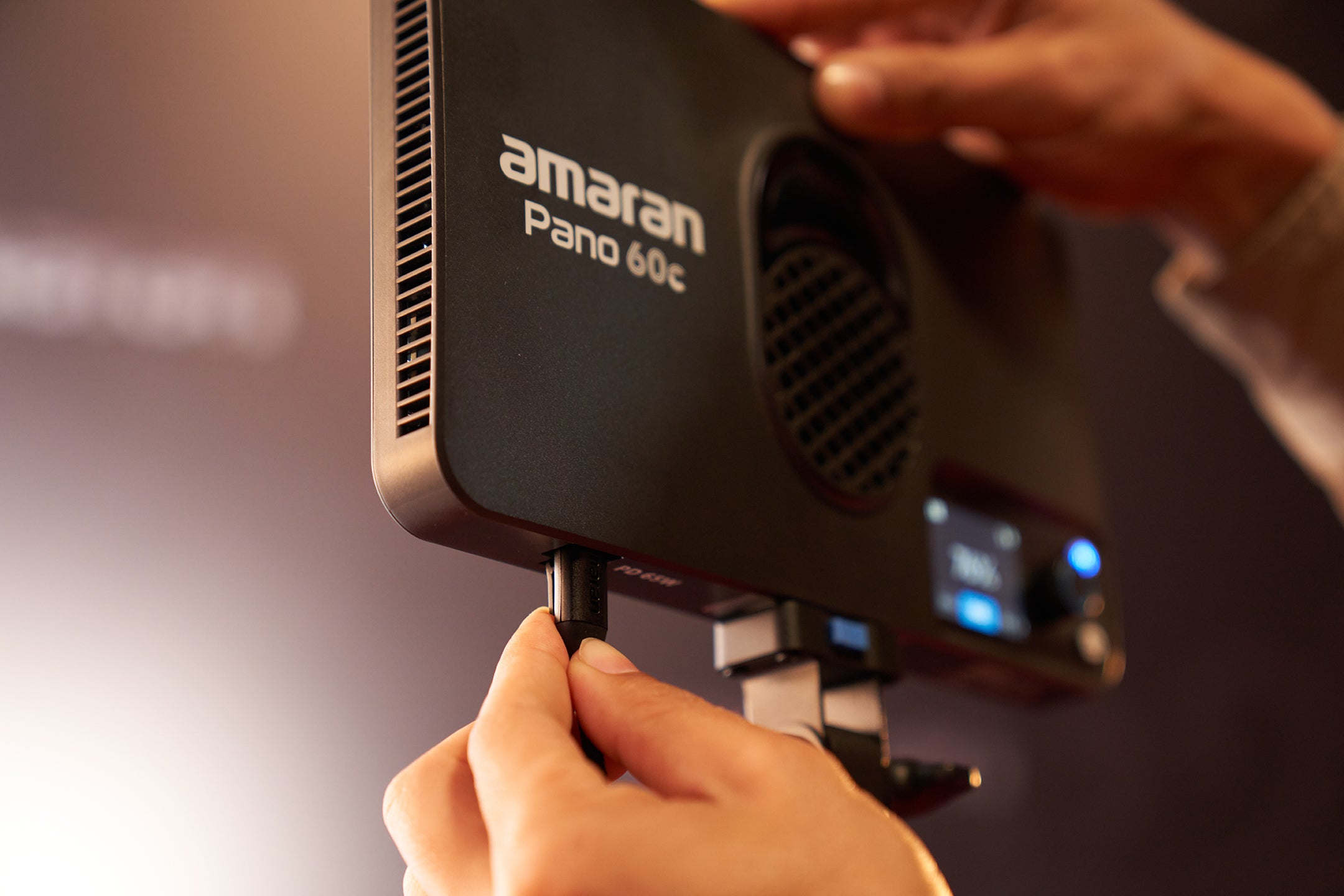 A person connecting a cable to the amaran Pano 60c.