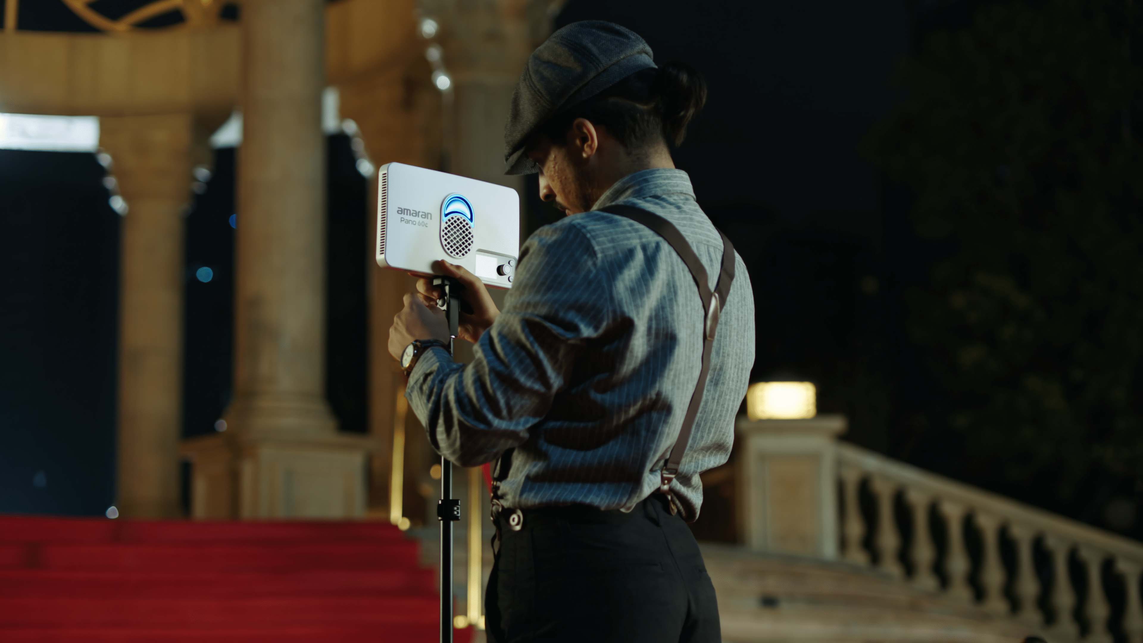 Technician connecting the amaran Pano 60c to a light stand on location.