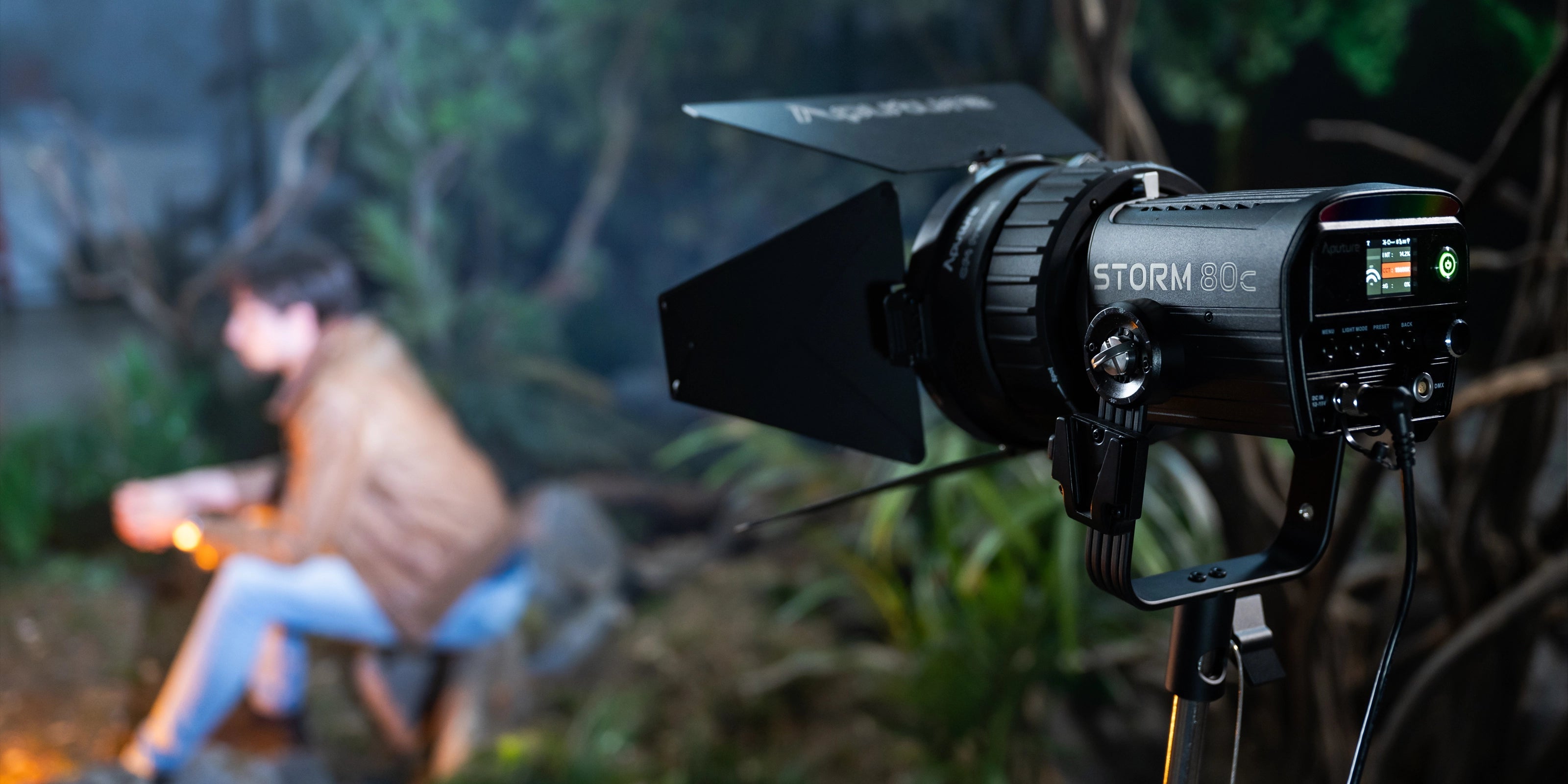 Aputure Storm 80c in. a night time scene with a purson out of focus in the jungle looking background.