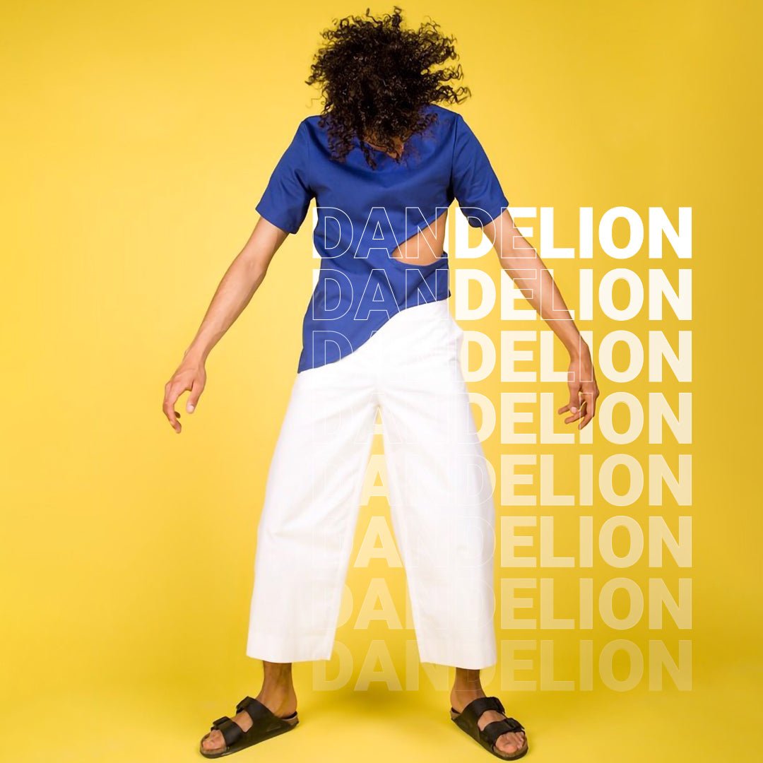 Model on Dandelion Colorama yellow coloured background, wearing a bright blue top and white trousers.