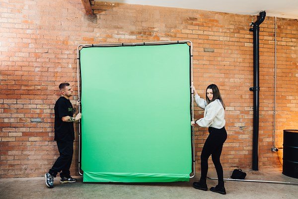 Two people setting up the Manfrotto Ezy Frame in a studio.