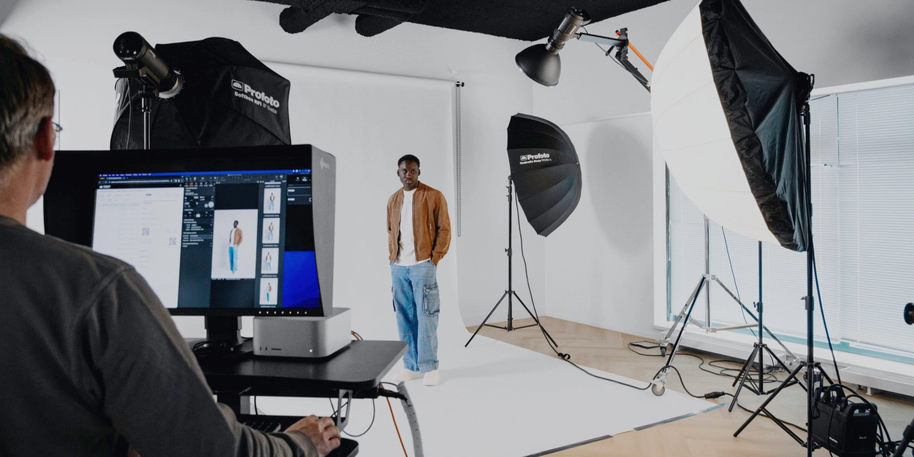 Male model in a studio envioment, stood on a seamless paper background surrounded by Profoto lights and a Digi operator in the foreground.