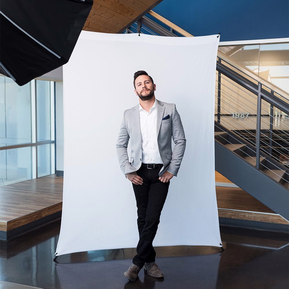 Man photographed against a white fabric strech background, shown in a modern rooftop scene.