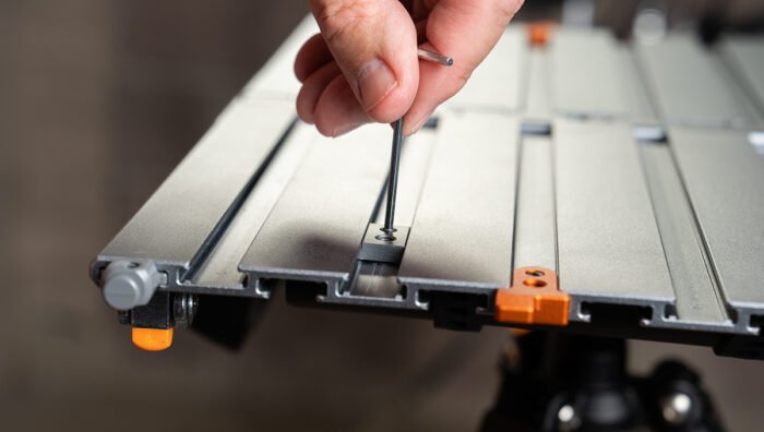 Person using a screwdriver on a Tether Tools AeroTrac Configuration Tool with a blurred background.