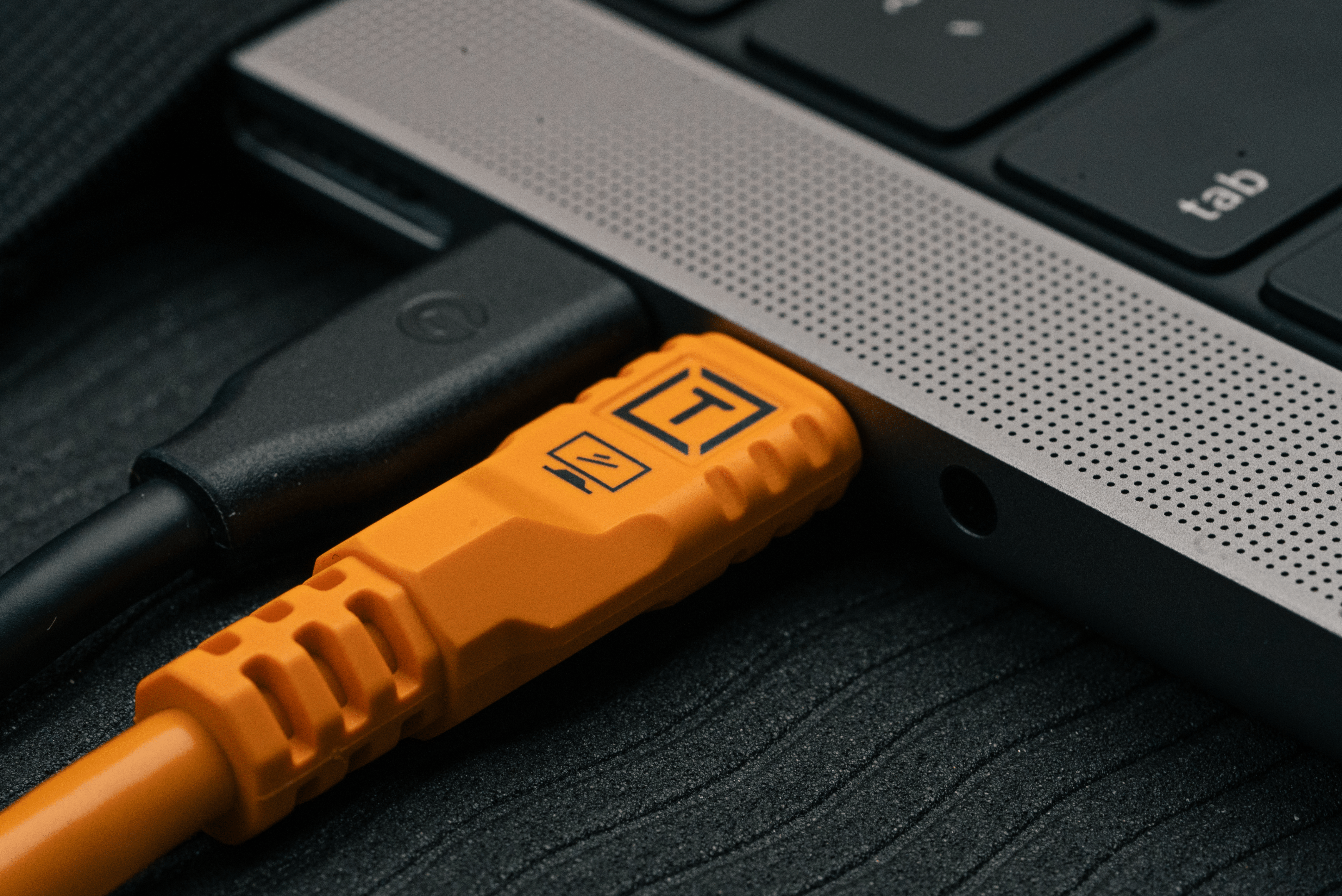 Close-up of a Tether Tools TetherPro Optima 10G USB-C, 10' (3m), Straight to Straight, High-Visibility Orange.