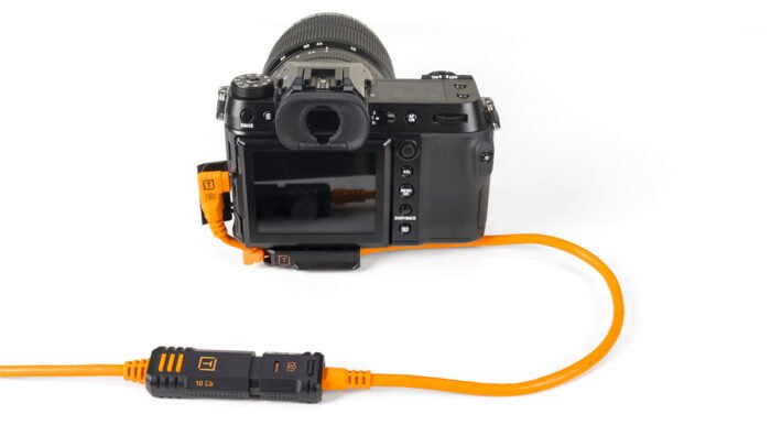 TetherPro Optima 10G TetherBoost Locking Extension Cable 16’ (4.8m) High Visibility Orange connected to a camera.