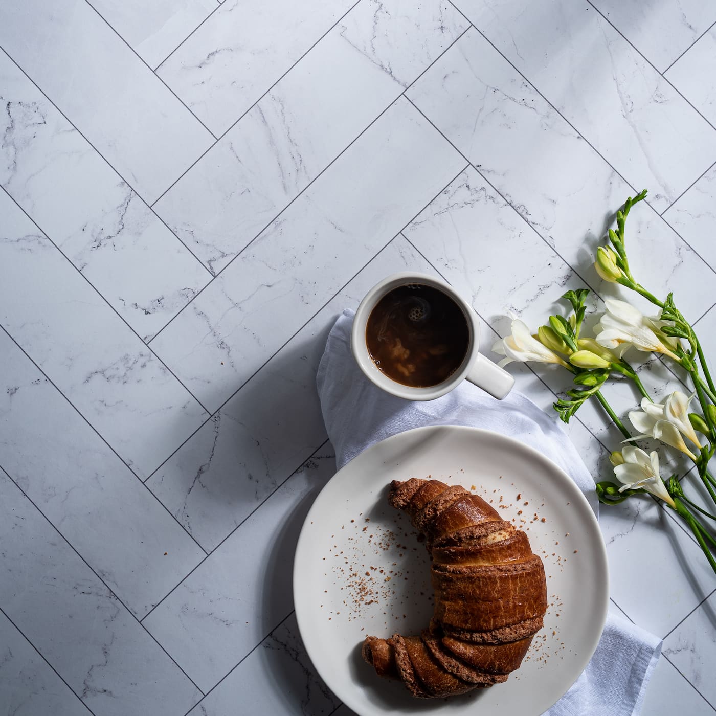 Zigzag Marble White/Zigzag Marble Black shown with coffee and croissant.