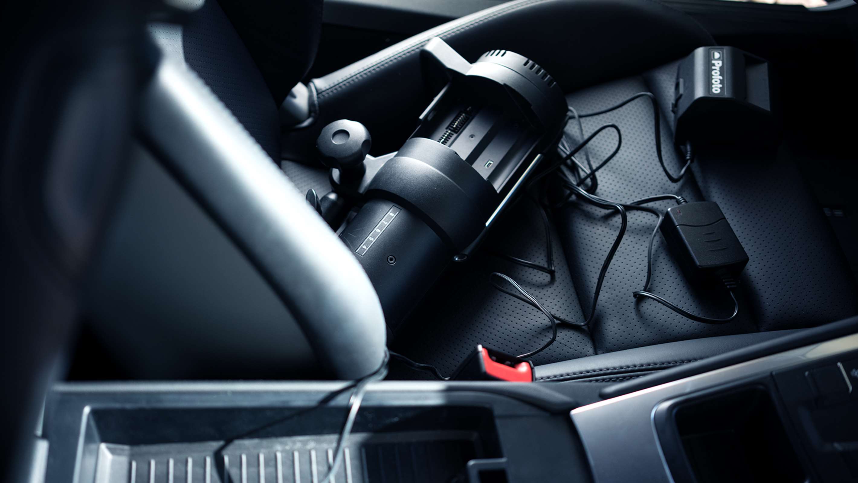 Profoto B1 and Profoto B1X & B1 Li-Ion Battery MkII shown on a car seat with charger.
