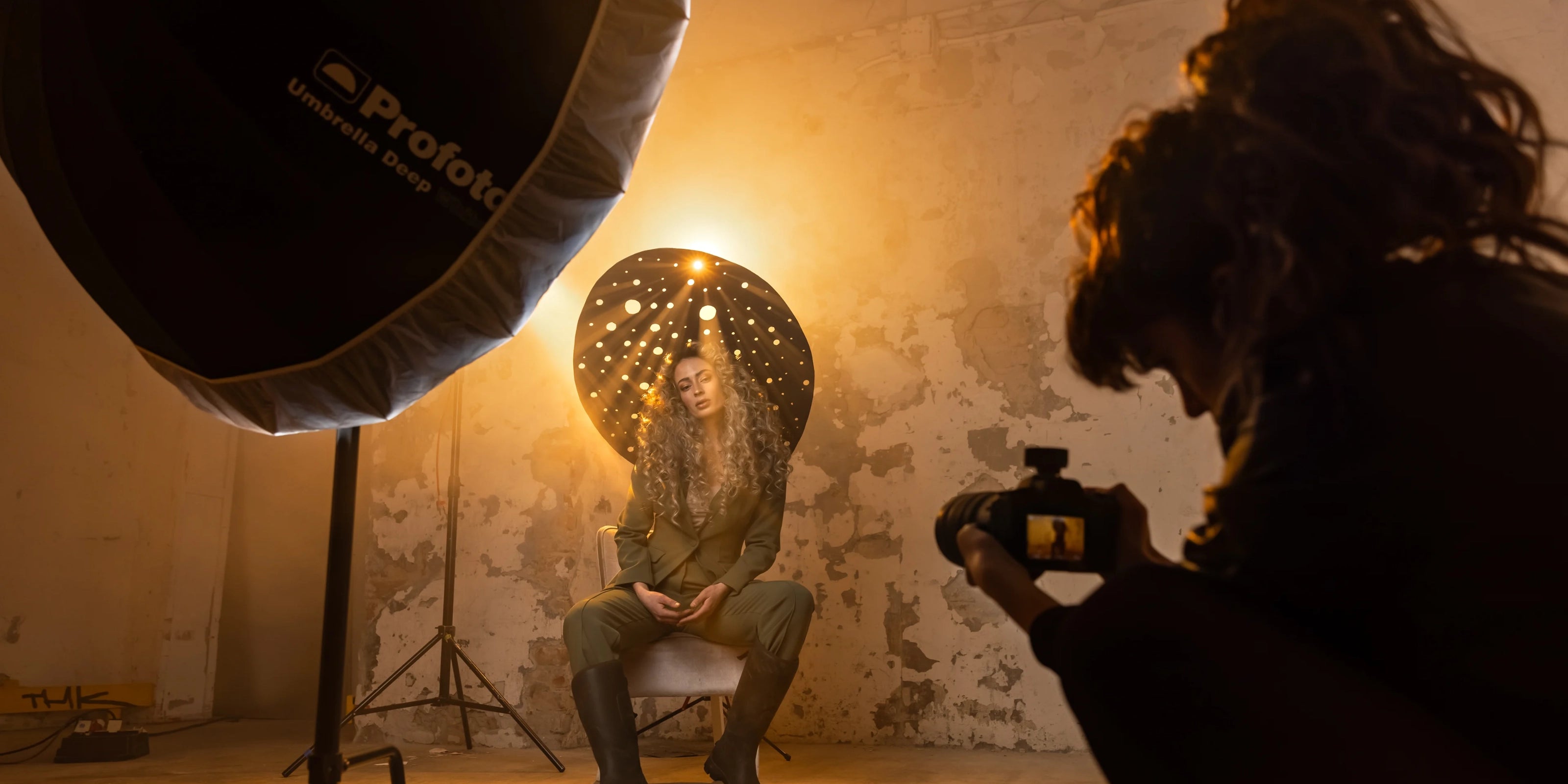 Person taking a photograph of another person with a Prolight studio light in a dimly lit room.