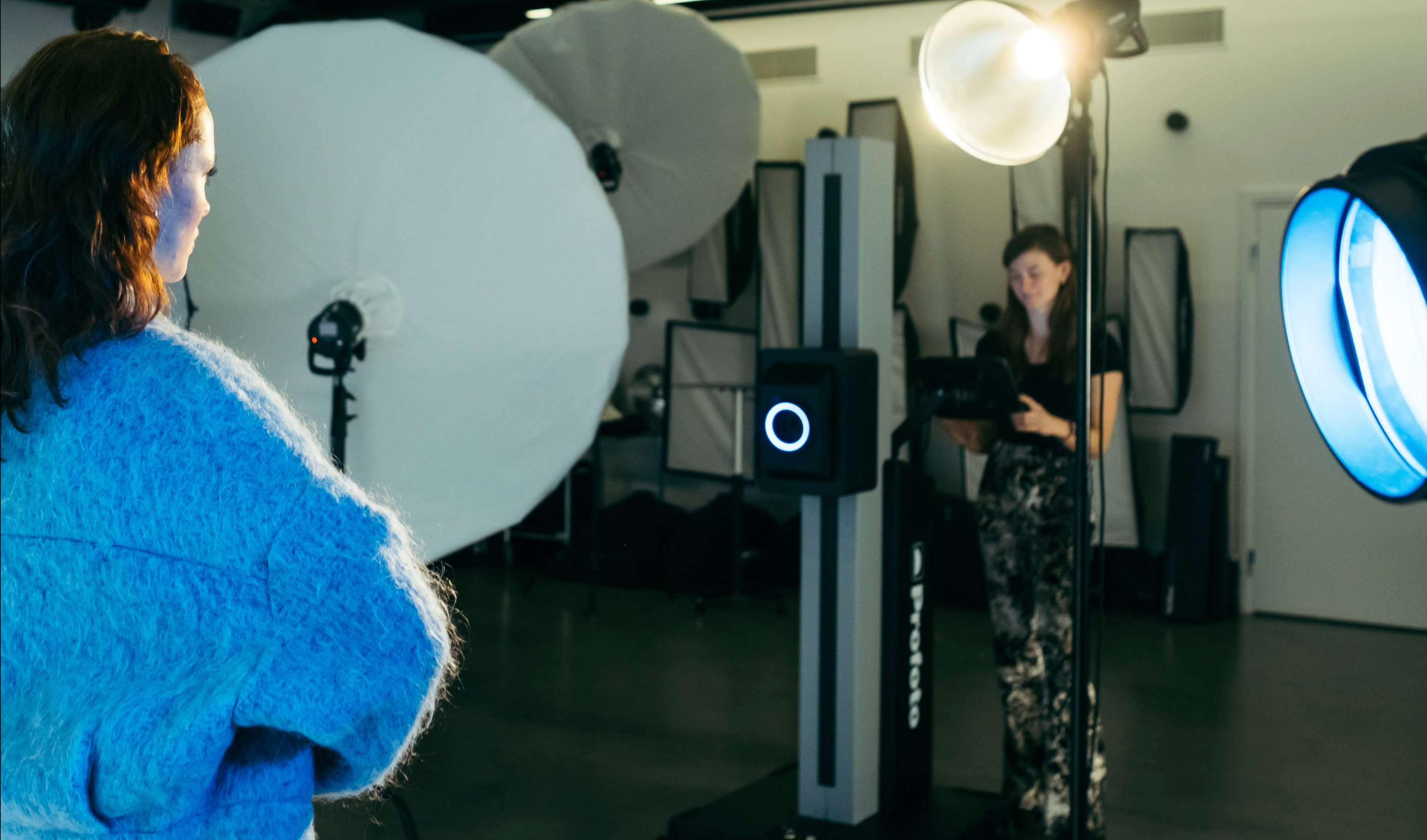 This image shows the operator using the Profoto Elevate, with various light shapers in the background and model in teh foreground wearing blue. 