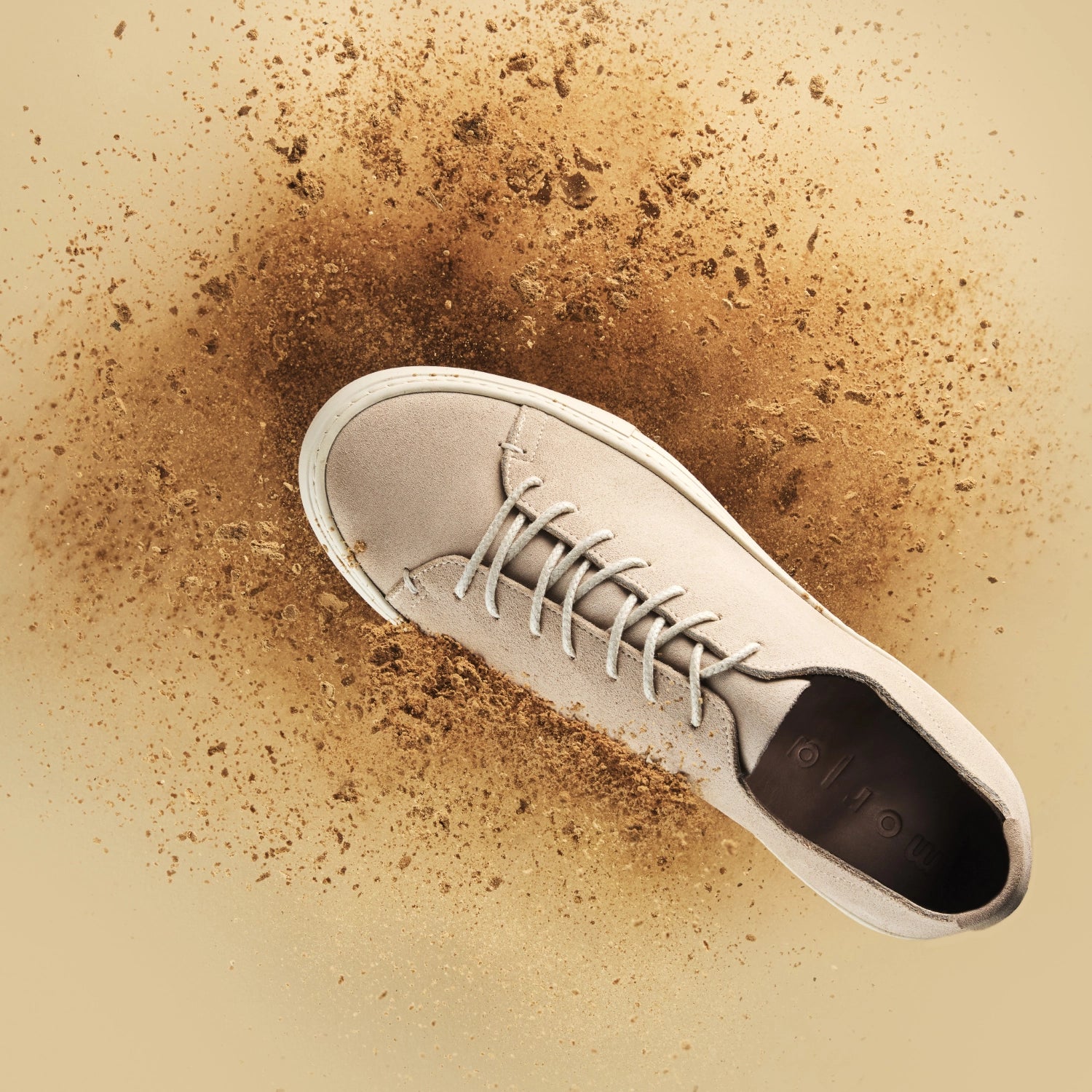 Snad coloured sneaker on a beige background with brown dirt. Image shot with the Profoto Pro-D3.
