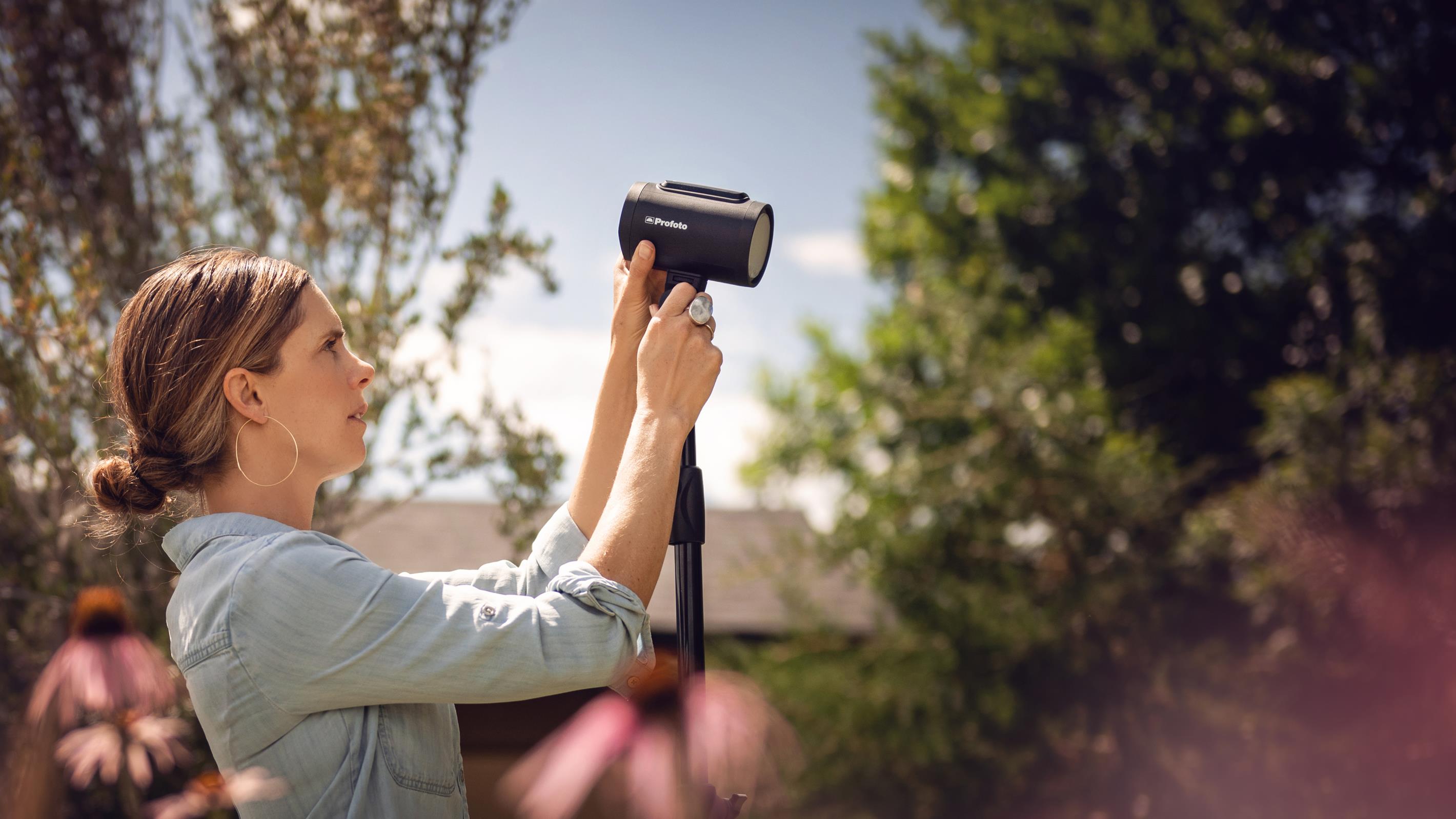 woman setting up Profoto A2 for an outdoor photoshoot