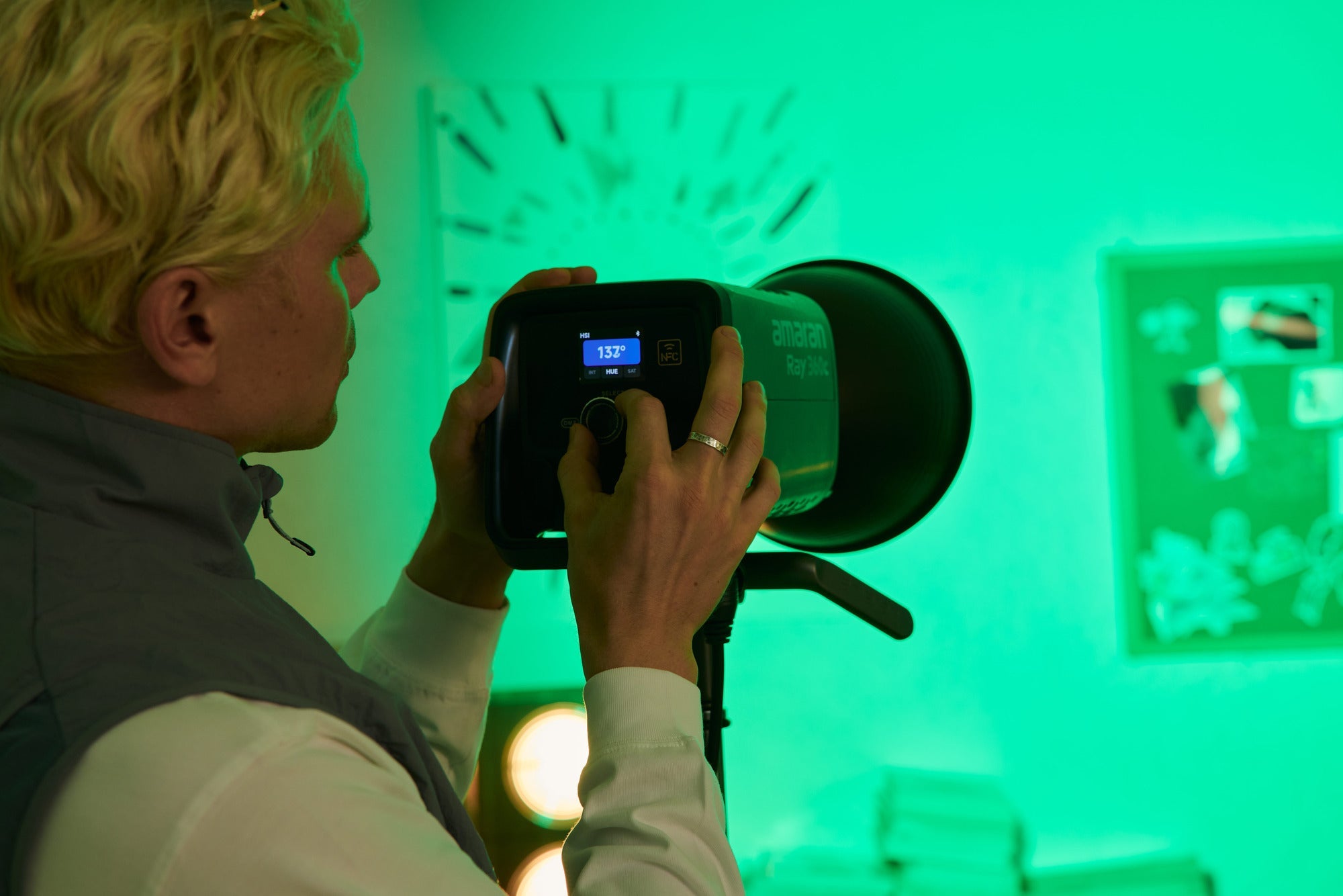 Person monitoring the amaran Ray 360 Light fixture in a studio.