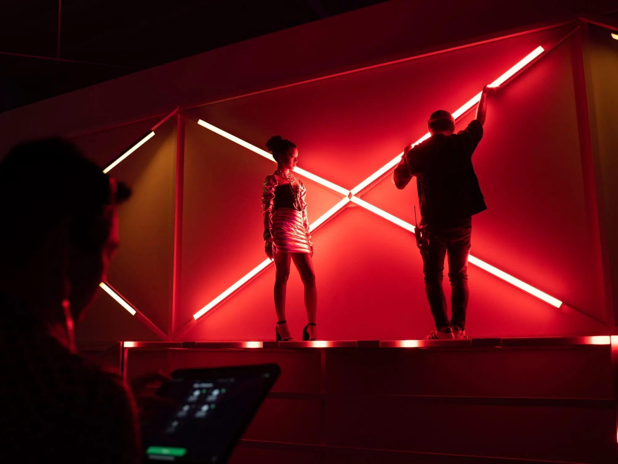 Two people adjusting INFINIBARS that are projecting red light.