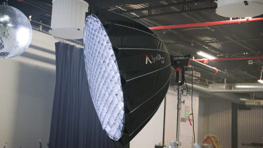 Aputure Light Dome 150 being utilised in a studio environment on a light stand with an Aputure 600d Pro CoB connected and a honeycomb grid attached.