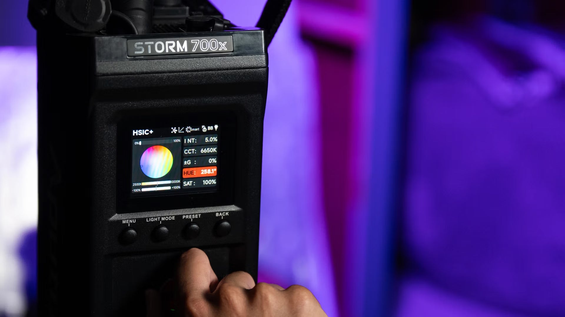Hand holding a device labeled 'STORM 700x' with a digital display against a blurred background.