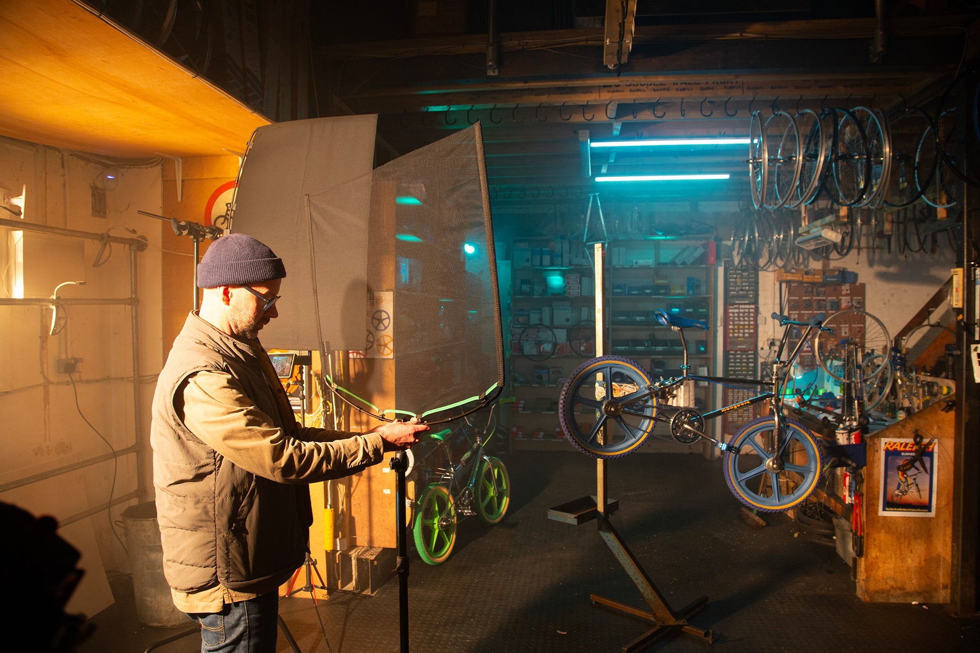 Inside a bike repair shop, showing a lighting technician setting up the Rapid Flag frame and Single Scrim.