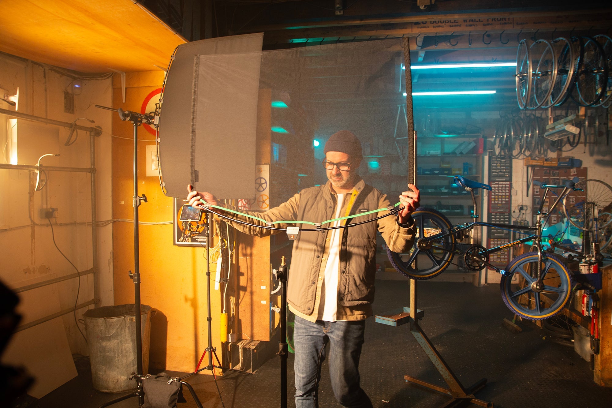 Inside a bike repair shop, showing a lighting technician setting up the Rapid Flag frame and Single Scrim.