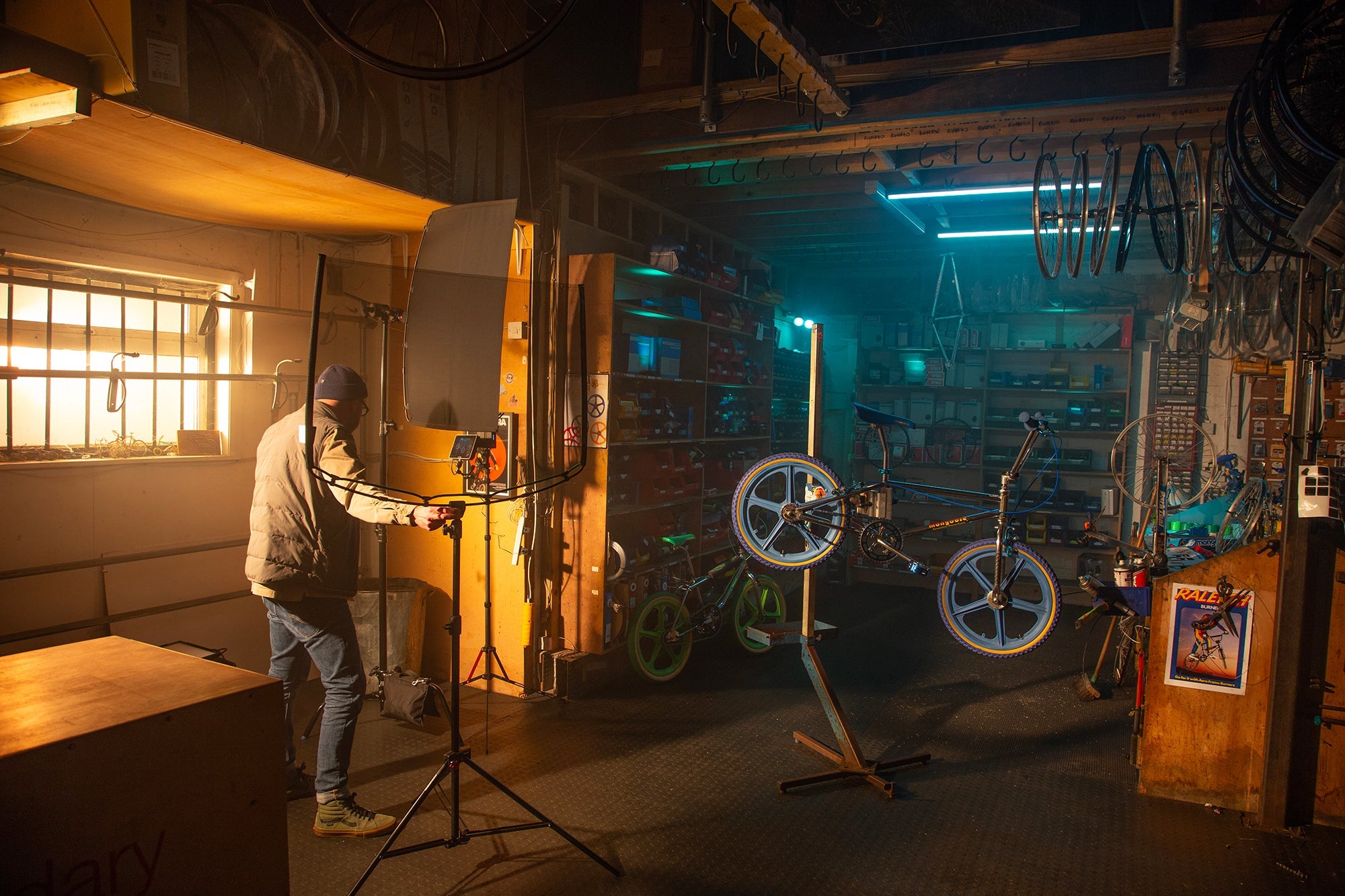 Inside a bike repair shop, showing a lighting technician setting up the Rapid Flag frame and Single Scrim.