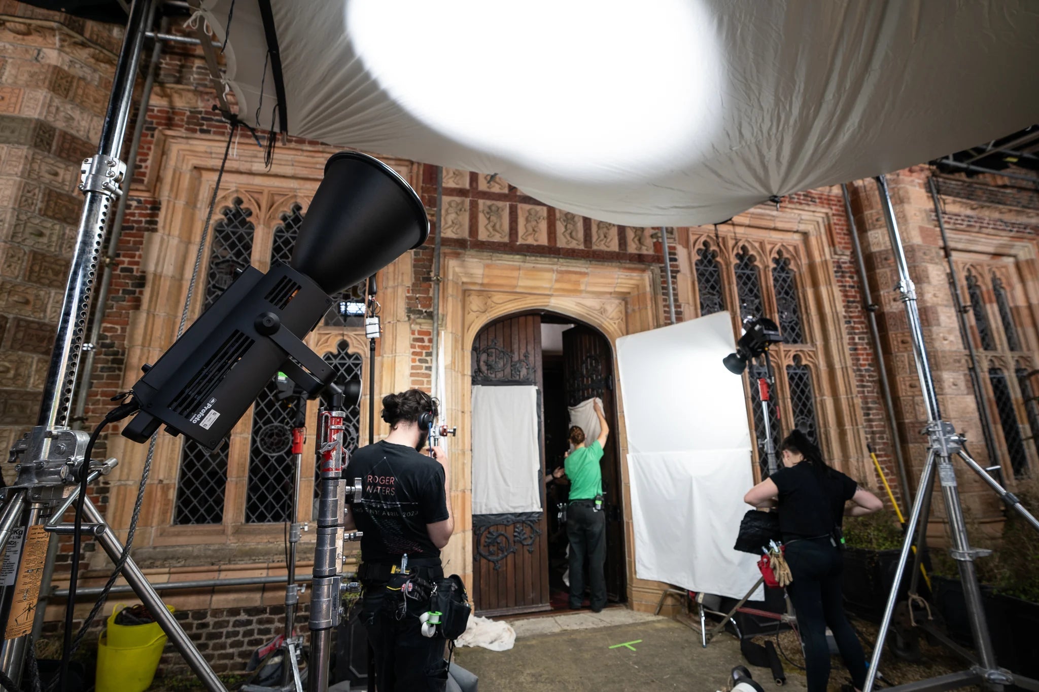 Film crew in a historic building with camera equipment and lighting setup.