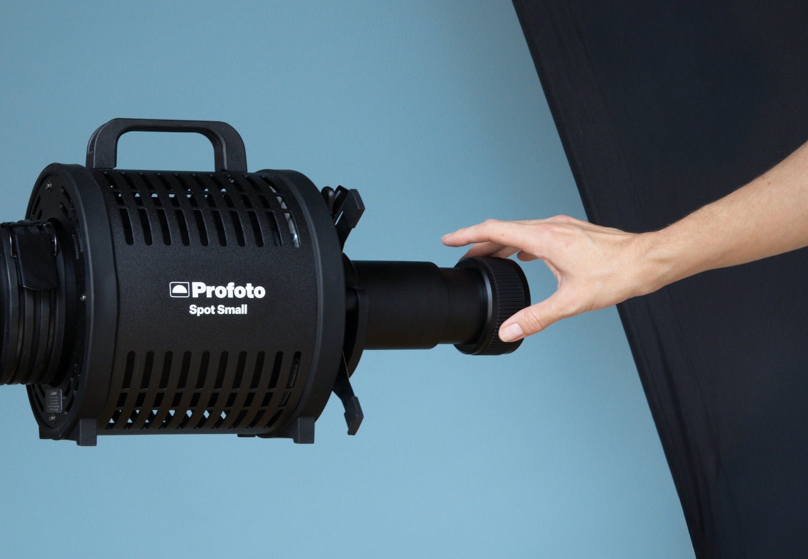 Person holding a Profoto Spot Small modifier against a blue background.