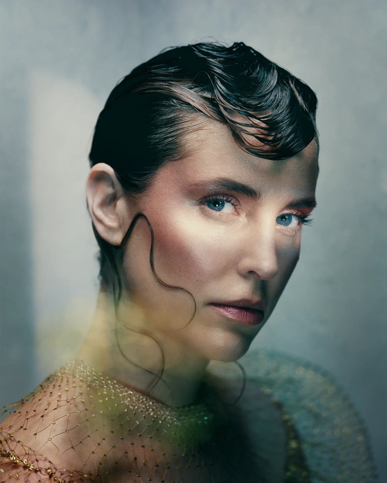 A colour photo of a model against a blue background with stylised hair.