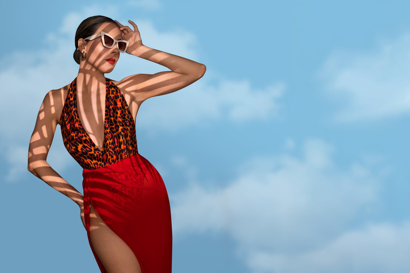 Female model with palm leaf effect projected on to her on a blue sky background. 