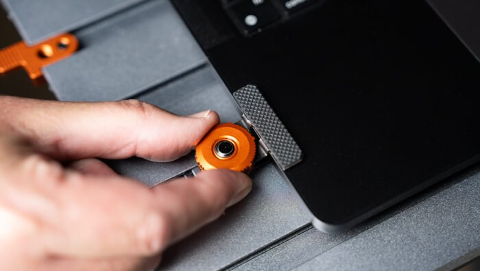 Close-up of the Tether Tools AeroTrac Tech Clamps (set of 2) attaching a laptop to the workstation.
