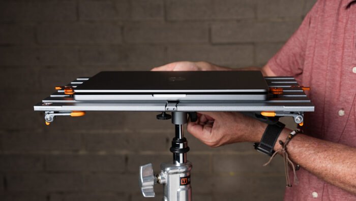 A person attaching a Tether Tools Rock Solid Baby Ballhead Adapter to a workstation. 