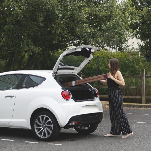 Person inserting a role of Colorama background paper into their car indicating its versatility and practicality.